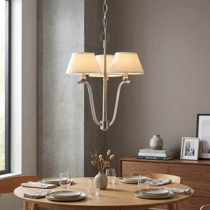 Hinkley Whitney 3-light brushed nickel chandelier with white fabric shades over a minimalist wooden dining table.