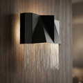 Modern wall light featuring an angular satin black casing and silver chain fringe, mounted on a wood-textured wall.