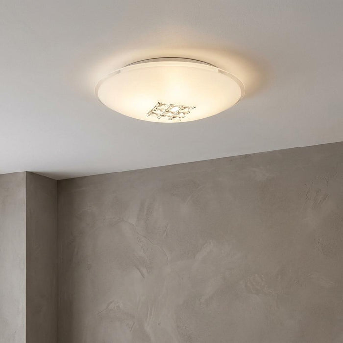 Horizon flush ceiling light featuring sanded glass and a crystal center, glowing against a grey wall.