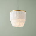Art Deco tiered white fringe pendant light with a gold rim against a sage green wall.