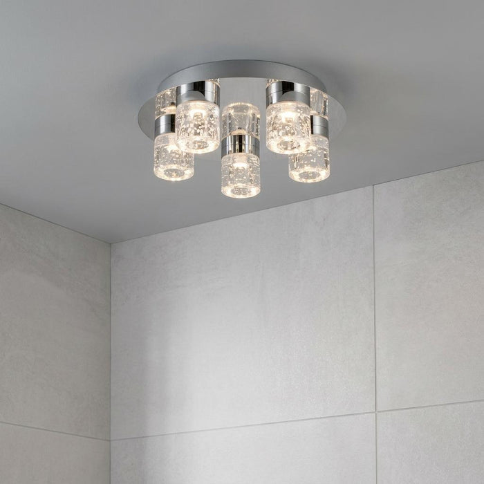 Modern 5-light chrome bathroom ceiling fixture with bubble glass cylinders mounted on a grey ceiling.