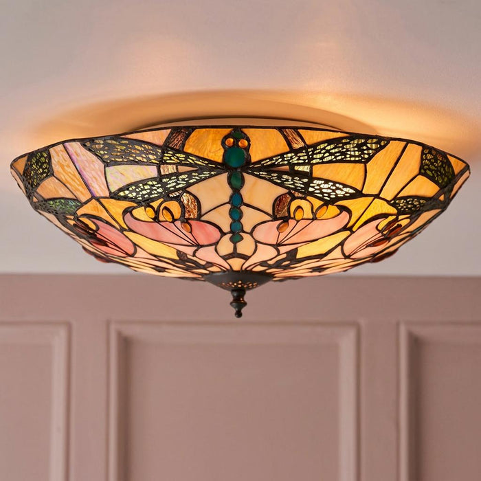 Dragonfly Tiffany-style flush ceiling light with amber and pink stained glass shade emitting a warm glow.