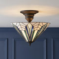 Art Deco semi-flush ceiling light with blue and white geometric stained glass panels against a navy blue wall.