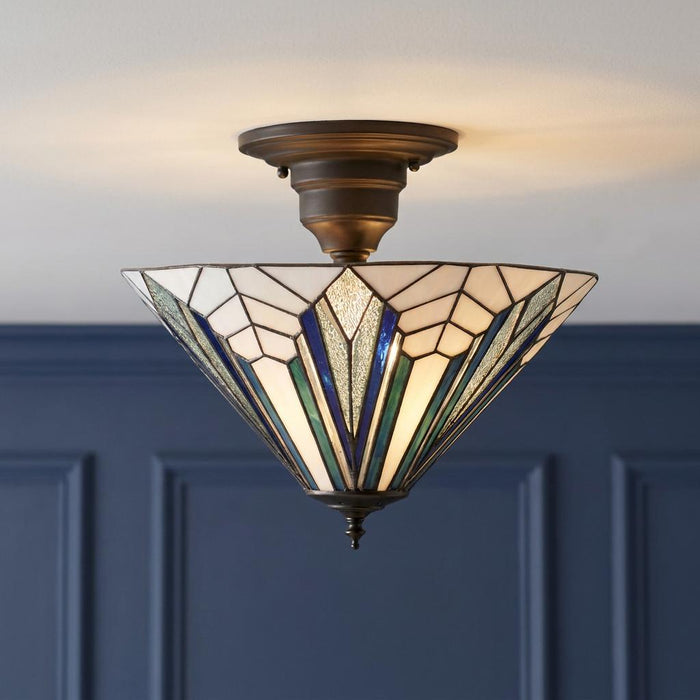 Art Deco semi-flush ceiling light with blue and white geometric stained glass panels against a navy blue wall.