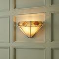 Art Deco Tiffany-style wall light with amber stained glass panels glowing on a light-colored paneled wall.