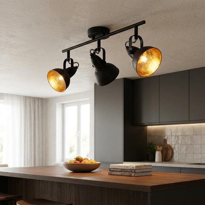 Jurva Urban black 3-light bar spotlight with gold interior, positioned over a modern wooden kitchen island.