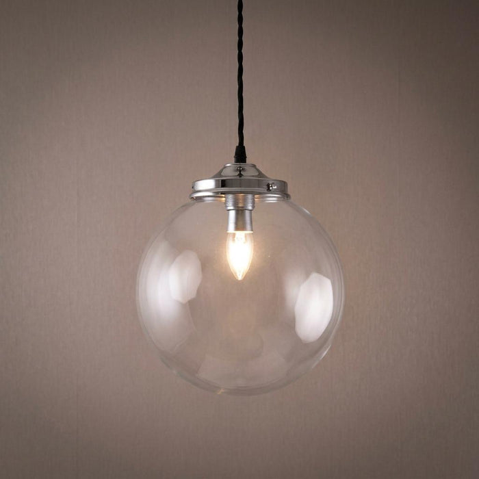 A lit clear glass globe pendant light with a polished chrome cap hanging against a neutral background.