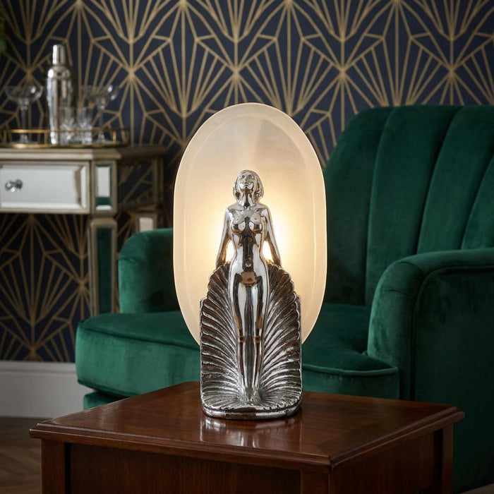 Art Deco female figurine lamp with frosted glass backplate on a wooden table in a stylish living room.
