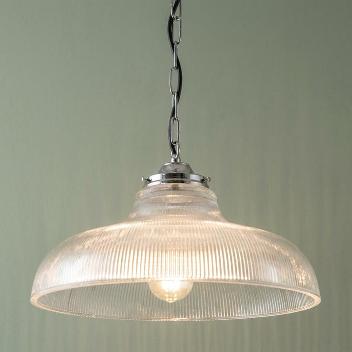 Traditional ceiling light with a ribbed clear glass dome shade and chrome chain hanging against a green wall.