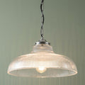 Traditional ceiling light with a ribbed clear glass dome shade and chrome chain hanging against a green wall.