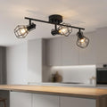 Black industrial three-head caged spot light bar mounted on a ceiling over a modern kitchen island.