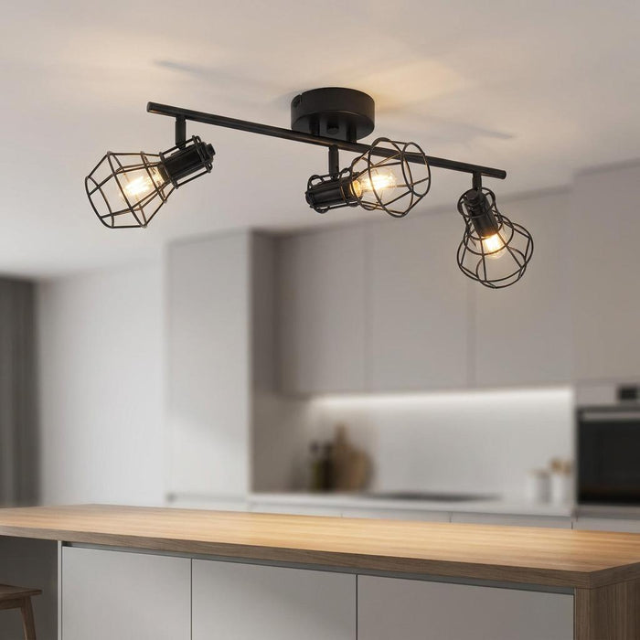 Black industrial three-head caged spot light bar mounted on a ceiling over a modern kitchen island.
