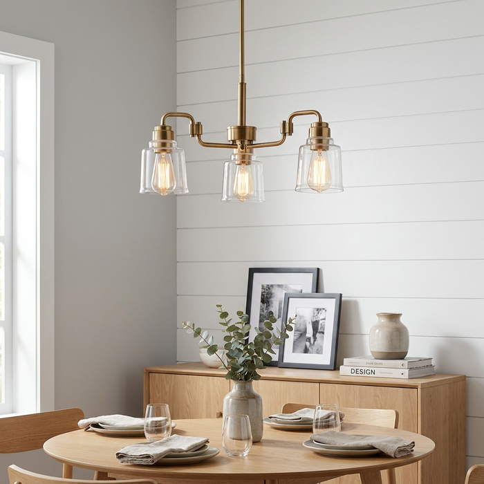 Kichler Avian three-light brass chandelier with clear glass shades hanging over a modern wooden dining table.