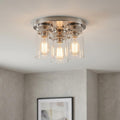 Brushed nickel three-light flush mount ceiling fixture with clear glass jar shades and glowing Edison bulbs.