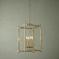 Brass lantern pendant light with four candle bulbs and crystal accents against a textured green background.