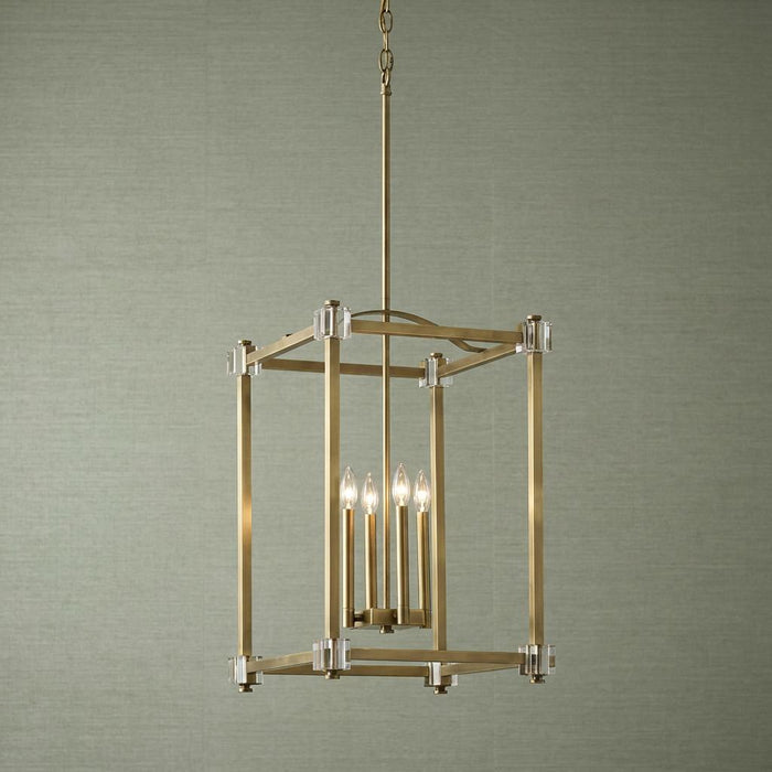 Brass lantern pendant light with four candle bulbs and crystal accents against a textured green background.
