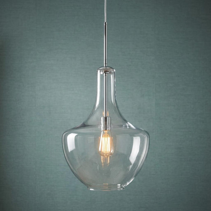 Chrome pendant light with a clear glass shade and warm Edison bulb against a textured teal wall.