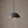 Textured charcoal dome pendant light with a scalloped edge and warm internal glow against a neutral wall.