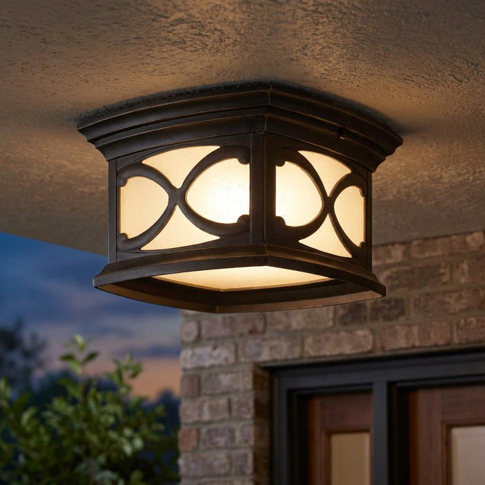 Traditional square bronze outdoor flush mount ceiling light with decorative lattice on a porch at dusk.