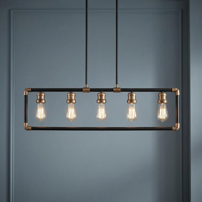 Industrial five-light linear chandelier with a black and brass frame and Edison bulbs against a blue wall.