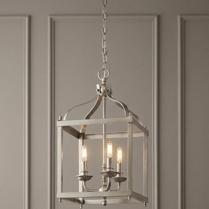 Kichler Larkin medium 3-light nickel ceiling lantern with a square frame and lit bulbs against a grey paneled wall.