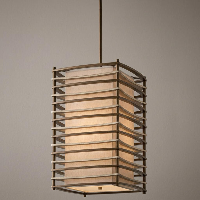 Large bronze pendant light with a fabric shade encased in a curved horizontal slat metal frame.