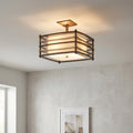Bronze semi-flush ceiling light with a slatted metal cage and linen shade, illuminated in a modern interior.