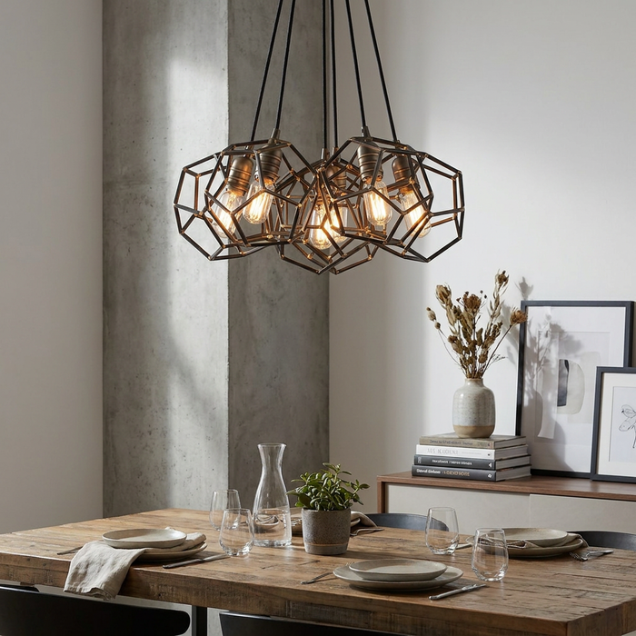 Kichler Rocklyn 6-light chandelier with raw steel geometric cages and Edison bulbs hanging over a wooden dining table.