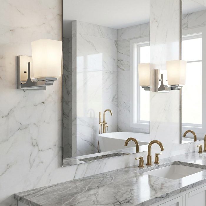 Kichler Roehm chrome bathroom wall light with a frosted glass shade mounted on a white marble wall next to a mirror.
