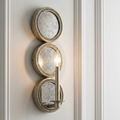 Kichler Rosalie gold wall sconce featuring three stacked antiqued mirror panels mounted on a white wall.