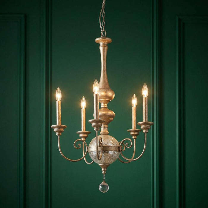 Five-light gold chandelier with a crackled glass orb and crystal drop, set against a dark green paneled wall.