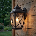 Bronze lantern outdoor wall light with seeded glass and lattice detail mounted on a wooden wall.