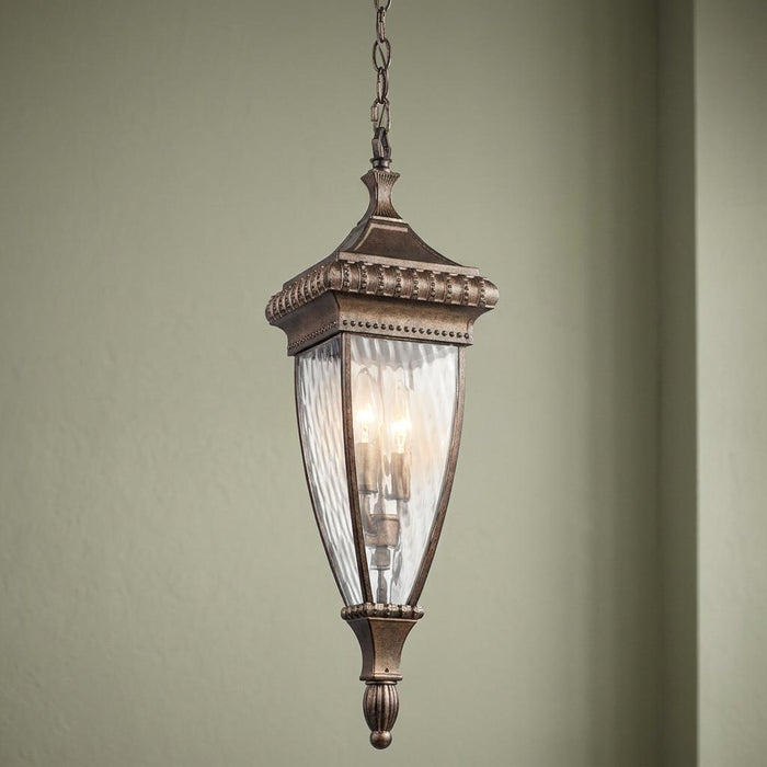 Ornate brushed bronze outdoor pendant light with rippled glass panels and a decorative lantern frame.
