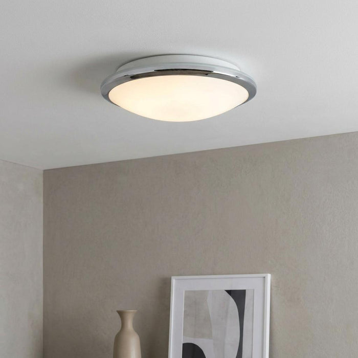 Knutsford flush ceiling light with chrome trim and frosted glass dome illuminated on a white ceiling.