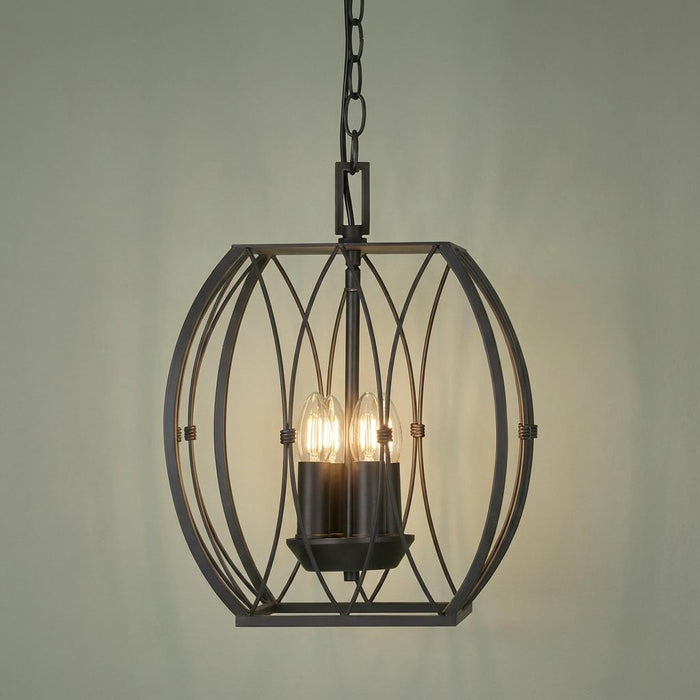 Four-light silver brushed black pendant with a geometric orb-shaped wire cage against a sage green wall.