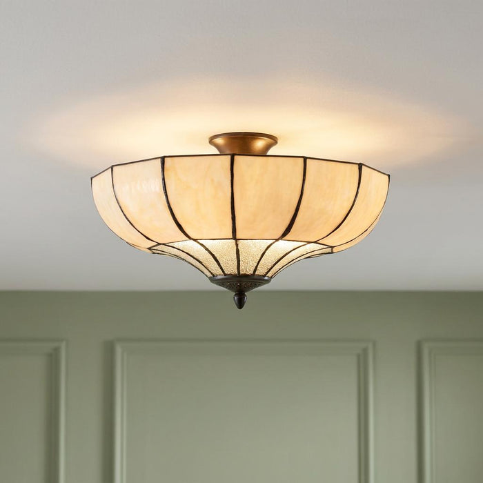 Art Deco semi-flush Tiffany ceiling light with amber glass panels glowing in a room with green panelled walls.