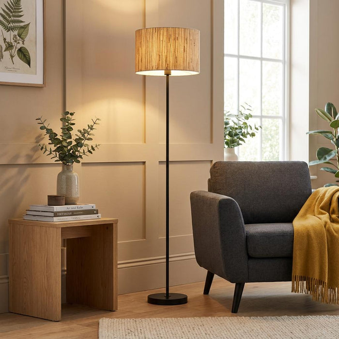 Longshore Black Floor Lamp with a wood-textured cylindrical shade in a cozy living room next to a gray armchair.
