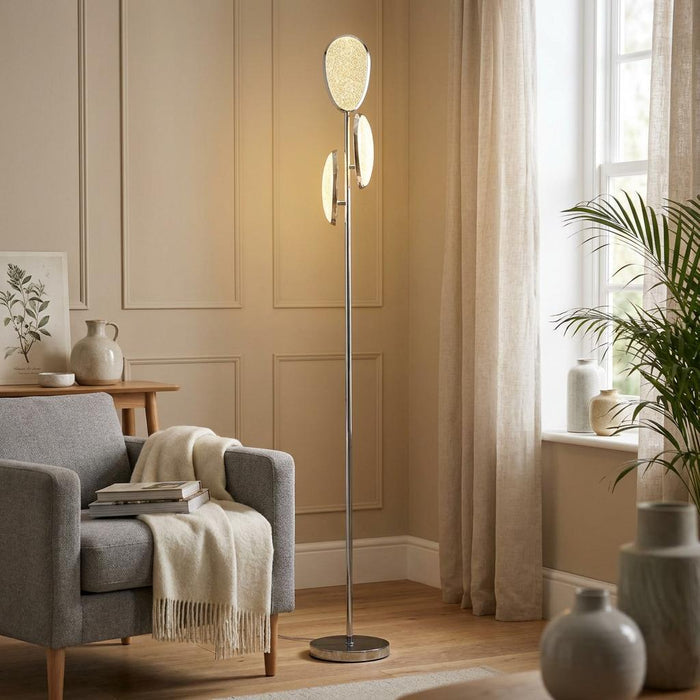 Lori chrome LED floor lamp with three glowing oval panels standing in a minimalist living room.