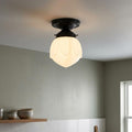 Lotus-shaped white frosted glass semi-flush ceiling light with a dark bronze mount in a minimalist room.
