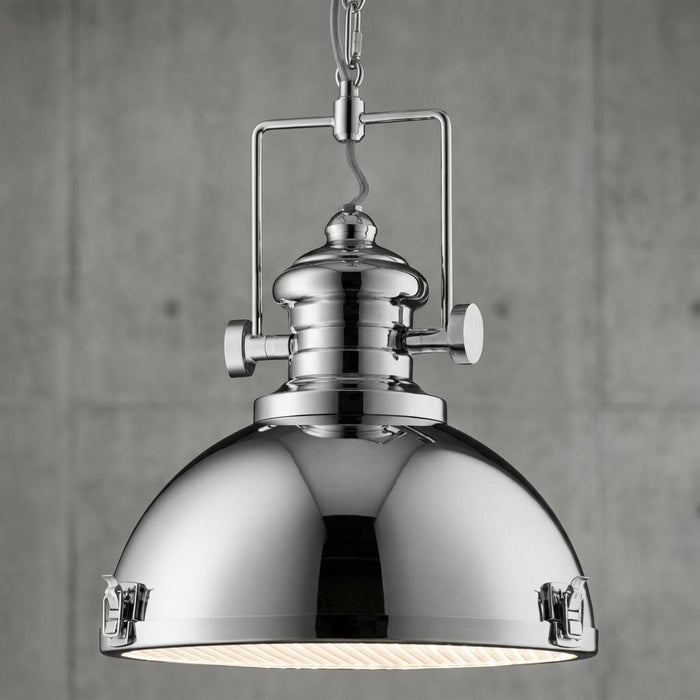 Polished chrome industrial searchlight pendant with a dome shade and decorative clasps against a concrete wall.