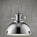 Polished chrome industrial searchlight pendant with a dome shade and decorative clasps against a concrete wall.