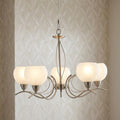 Luanda 5 light antique chrome chandelier with frosted glass shades against a neutral patterned wall.