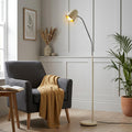 Madison cream floor lamp with a curved chrome arm illuminates a cozy reading nook with a grey armchair.