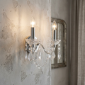 Marie Therese 2 light acrylic wall light with crystal droplets mounted on a textured stone wall.