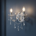 Lit Marie Therese 2 light chrome and crystal glass wall sconce with droplets on a dark blue wall.