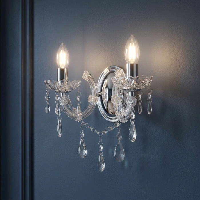 Lit Marie Therese 2 light chrome and crystal glass wall sconce with droplets on a dark blue wall.