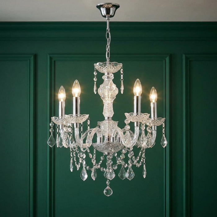 Marie Therese 5-light acrylic chandelier with decorative crystals lit against a dark green wood-paneled wall.