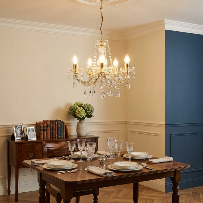 Marie Therese 5 Light Polished Brass and Crystal Chandelier hanging over a set wooden dining table in a classic room.