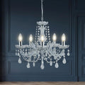 Marie Therese 5 light chrome and crystal glass chandelier with hanging droplets against a dark blue paneled wall.