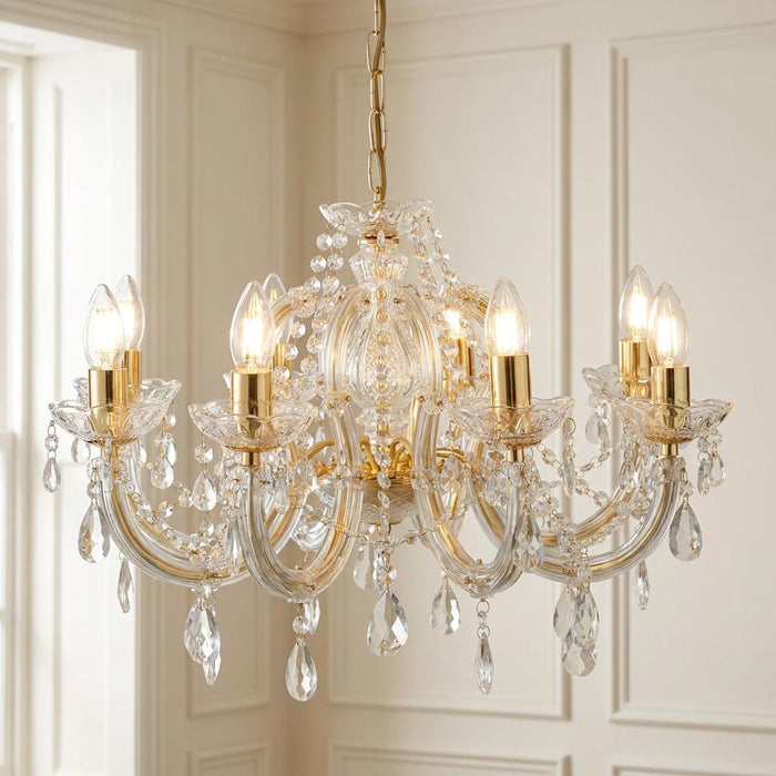 Marie Therese 8-light brass and clear crystal chandelier with teardrop droplets against a paneled wall.